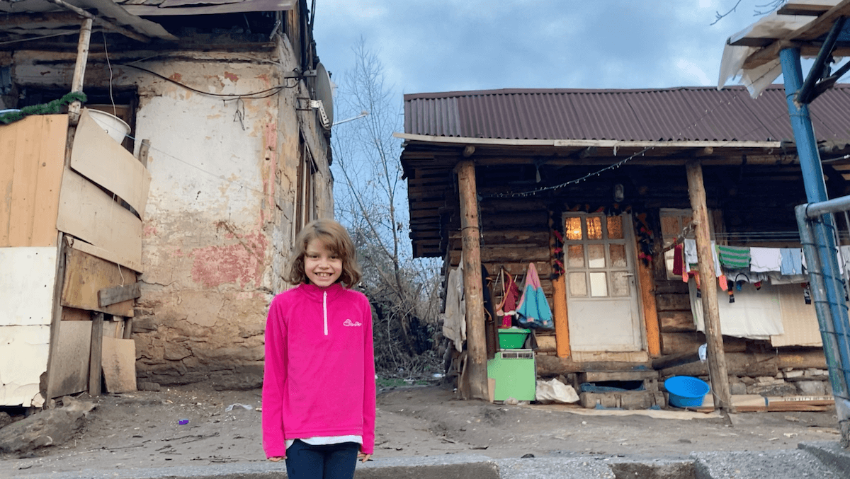 Dívka v romské osadě před chatrčí svých rodičů